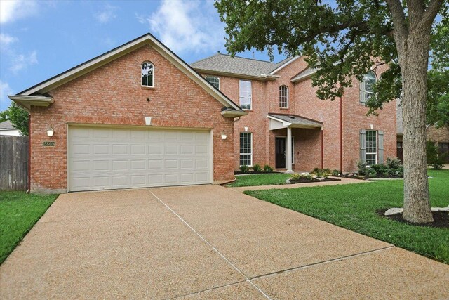 traditional-style house featuring concrete driveway, brick siding, a garage, and a front lawn