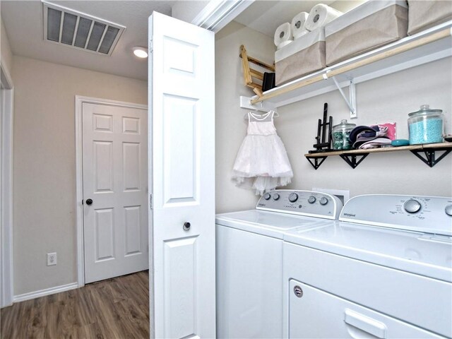 washroom with laundry area, baseboards, wood finished floors, visible vents, and washer and clothes dryer