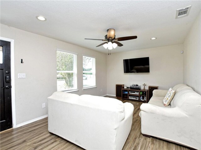 living area with a ceiling fan, visible vents, and wood finished floors