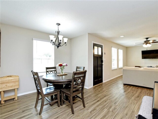 dining area featuring baseboards, ceiling fan with notable chandelier, and light wood-style floors