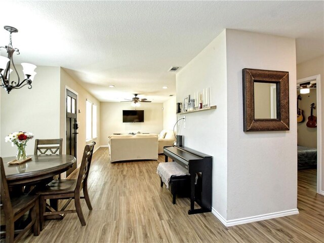 dining space featuring visible vents, baseboards, ceiling fan with notable chandelier, and light wood-type flooring