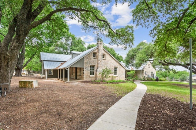 1504 Maier Dr, Pflugerville, TX 78660 - view of property exterior with stone siding, a chimney, metal roof, and a yard