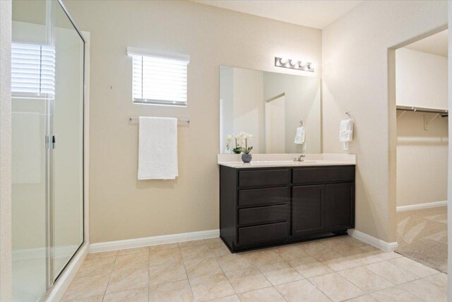 bathroom featuring vanity, baseboards, tile patterned floors, and a stall shower