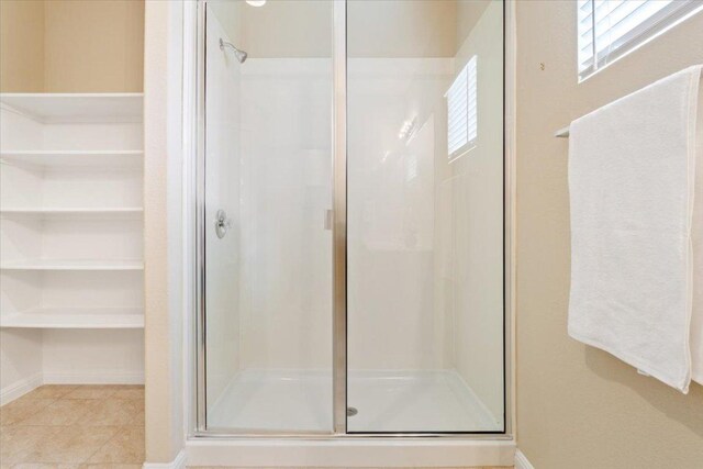full bathroom with baseboards, tile patterned flooring, and a shower stall