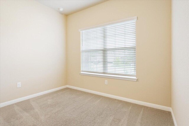 carpeted empty room featuring baseboards