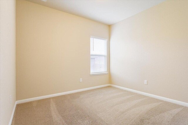 spare room featuring baseboards and light carpet