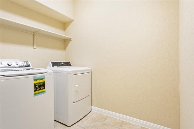 washroom with light tile patterned floors, separate washer and dryer, baseboards, and laundry area