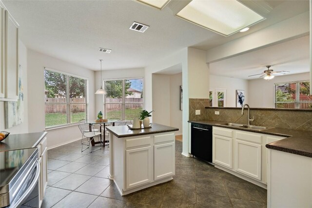 kitchen featuring dark countertops, a sink, dishwasher, tasteful backsplash, and visible vents