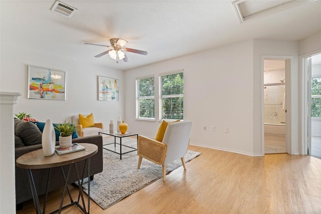 living area with plenty of natural light, light wood-type flooring, ceiling fan, and visible vents