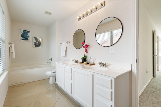 bathroom with double vanity, a bath, visible vents, a sink, and toilet