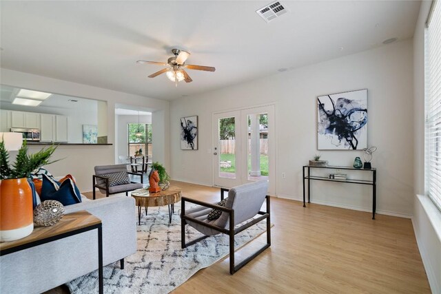 living area featuring visible vents, a ceiling fan, baseboards, and light wood-type flooring