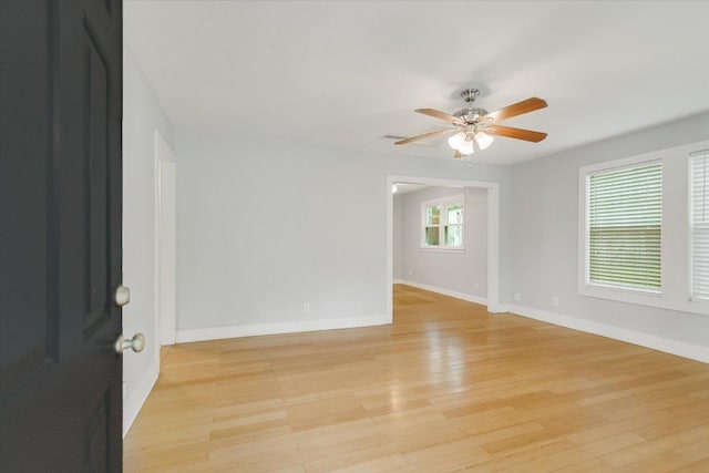 spare room with baseboards, ceiling fan, and light wood-style flooring