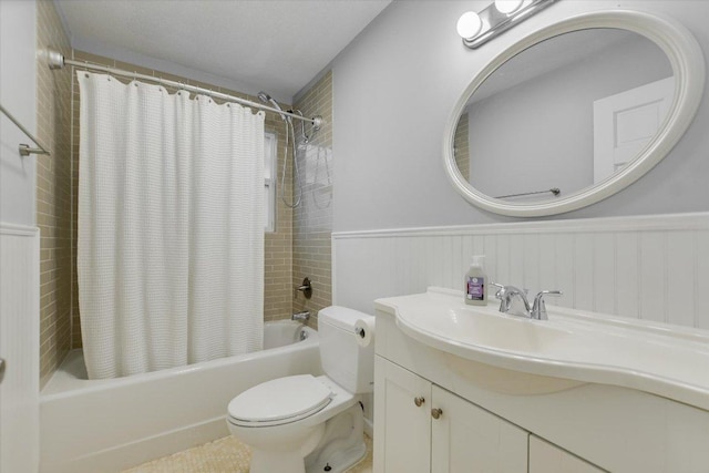bathroom with a wainscoted wall, shower / bath combo with shower curtain, vanity, and toilet