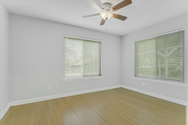 empty room with baseboards, a ceiling fan, wood finished floors, and a healthy amount of sunlight