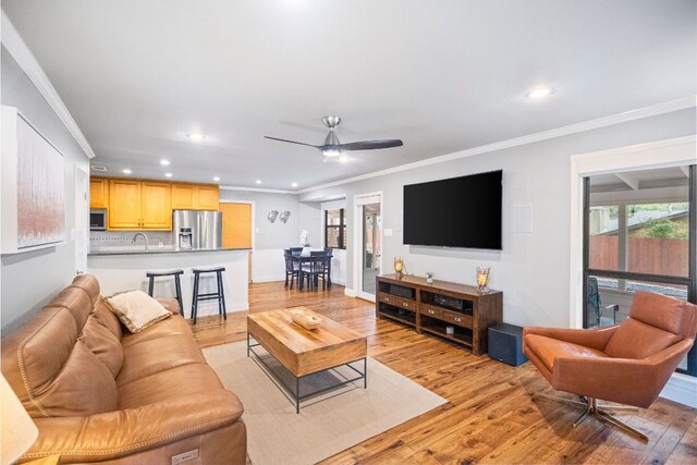 living room with crown molding, recessed lighting, and light wood-style floors