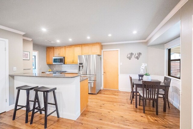kitchen featuring crown molding, light brown cabinetry, light wood-type flooring, stainless steel appliances, and recessed lighting