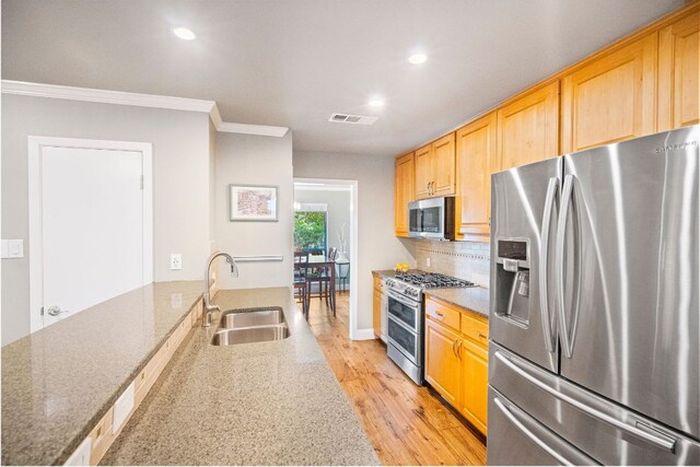 kitchen featuring crown molding, visible vents, a sink, light wood-style flooring, and appliances with stainless steel finishes