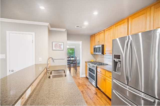 2100 Four Oaks Ln, Austin, TX 78704 - kitchen featuring appliances with stainless steel finishes, a sink, ornamental molding, light wood-style floors, and light stone counters