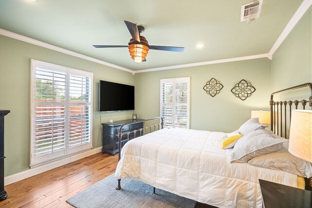 bedroom with multiple windows, ornamental molding, hardwood / wood-style floors, and visible vents