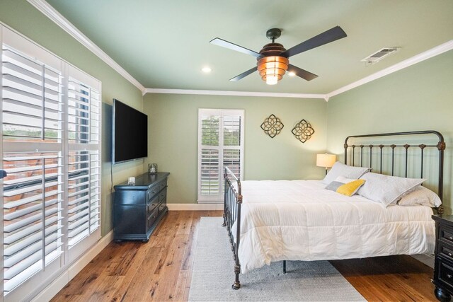 bedroom with crown molding, baseboards, visible vents, and wood finished floors