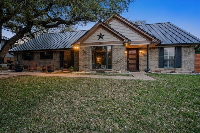 craftsman-style home featuring a standing seam roof, metal roof, a front lawn, and brick siding