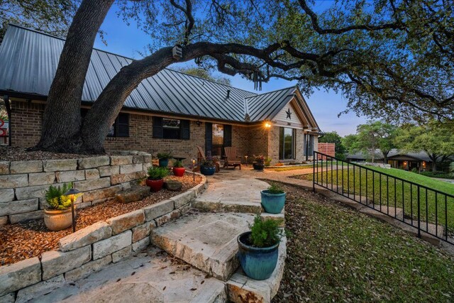 back of property with fence, brick siding, a patio area, a standing seam roof, and metal roof