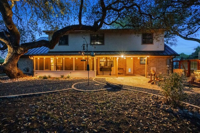 back of house with a standing seam roof, metal roof, and brick siding