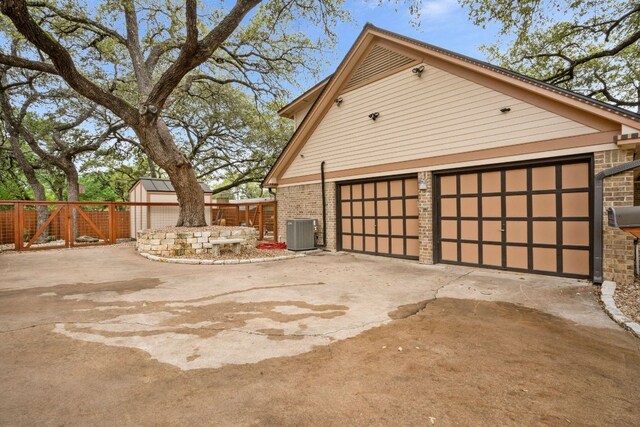2100 Four Oaks Ln, Austin, TX 78704 - view of home's exterior with central air condition unit, a garage, an outbuilding, brick siding, and driveway