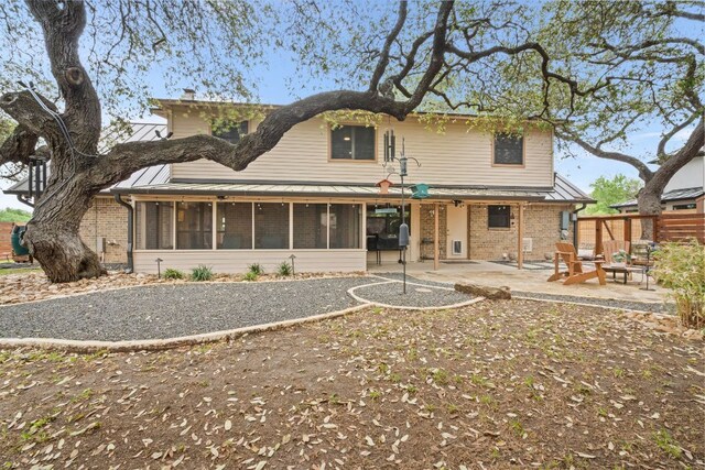 2100 Four Oaks Ln, Austin, TX 78704 - rear view of property featuring a sunroom, a patio, brick siding, and a standing seam roof
