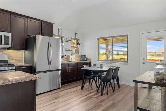 kitchen with backsplash, dark brown cabinets, light stone counters, light wood finished floors, and stainless steel appliances
