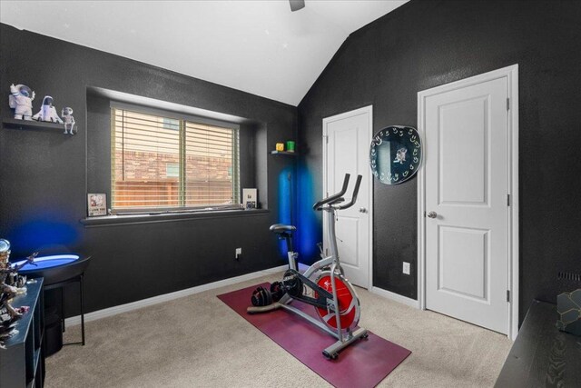 exercise room featuring carpet floors, baseboards, and vaulted ceiling
