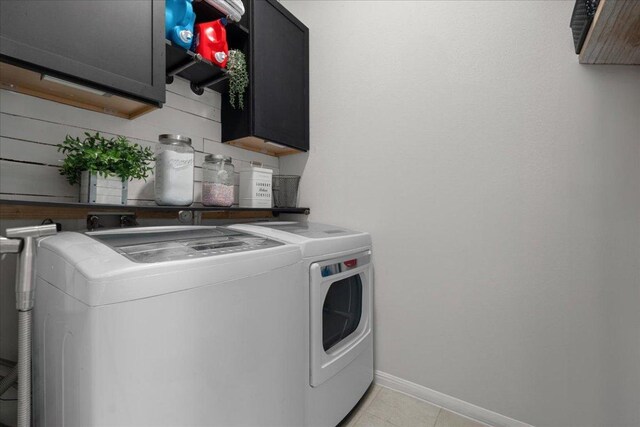 laundry room featuring light tile patterned floors, baseboards, washing machine and dryer, and cabinet space