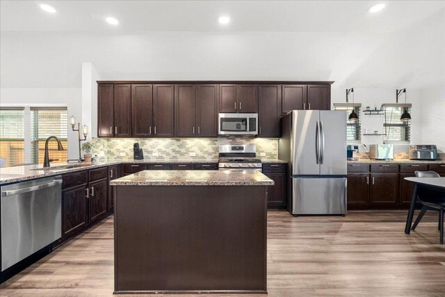 kitchen featuring a sink, dark brown cabinetry, stainless steel appliances, and stone counters