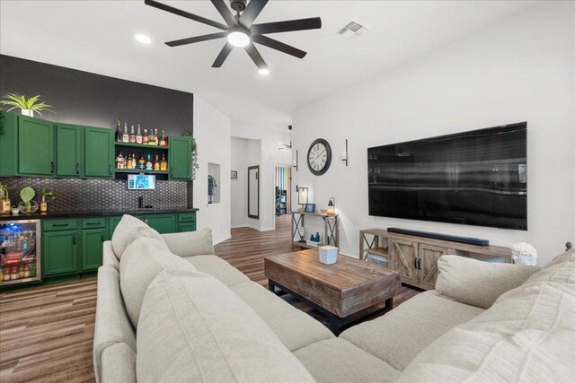 living area featuring light wood-style floors, beverage cooler, a ceiling fan, wet bar, and visible vents