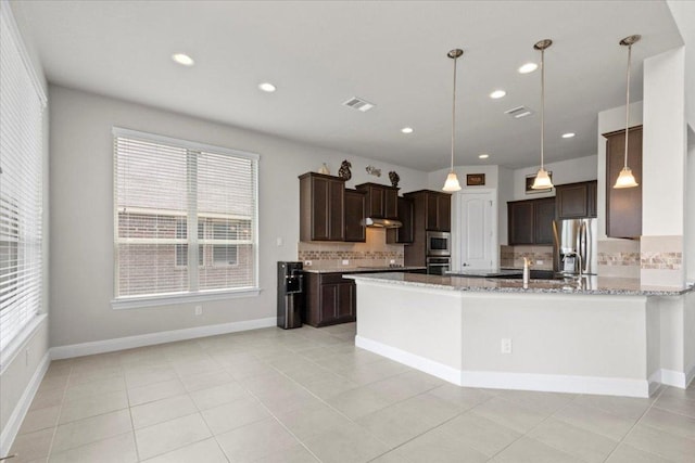 1800 Erie Dr, Leander, TX 78641 - kitchen with stainless steel appliances, tasteful backsplash, dark brown cabinets, plenty of natural light, and recessed lighting