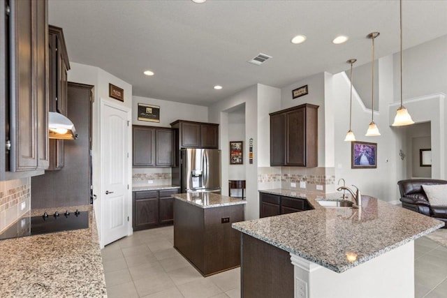 1800 Erie Dr, Leander, TX 78641 - kitchen with stainless steel fridge with ice dispenser, dark brown cabinets, backsplash, and recessed lighting