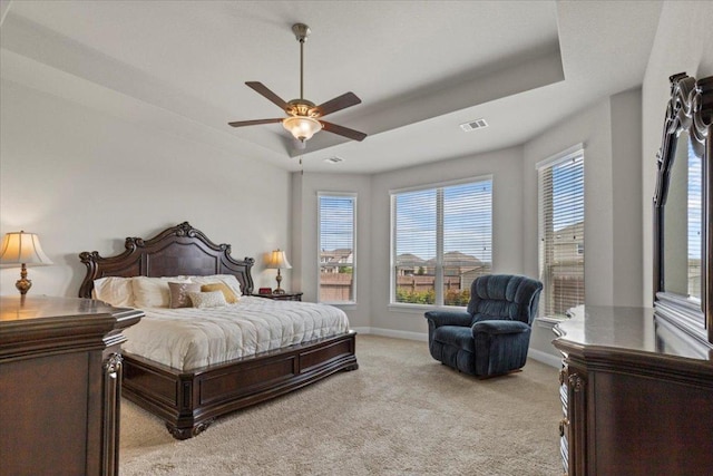 1800 Erie Dr, Leander, TX 78641 - bedroom featuring light carpet, multiple windows, a tray ceiling, and a ceiling fan