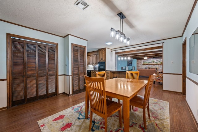 3909 Alderwood Ln, Temple, TX 76502 - dining space featuring wood finished floors, crown molding, a textured ceiling, and a wainscoted wall