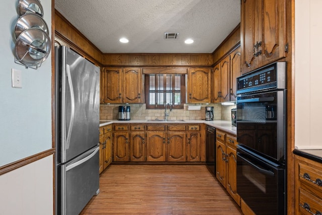 3909 Alderwood Ln, Temple, TX 76502 - kitchen with black appliances, brown cabinets, a textured ceiling, backsplash, and recessed lighting