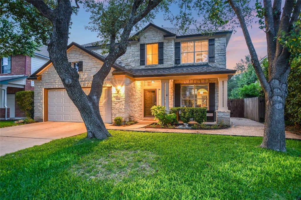 3768 Turetella Dr, Round Rock, TX 78681 - traditional-style house featuring fence, stone siding, a yard, an attached garage, and driveway