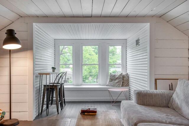 living room with wood walls, vaulted ceiling, hardwood / wood-style flooring, and a wealth of natural light