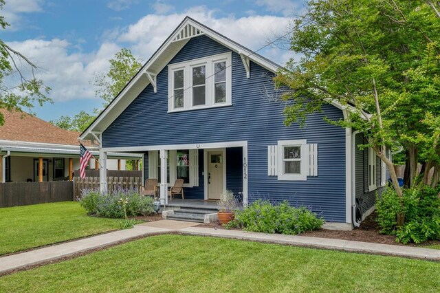 bungalow-style home featuring a front lawn, fence, and covered porch