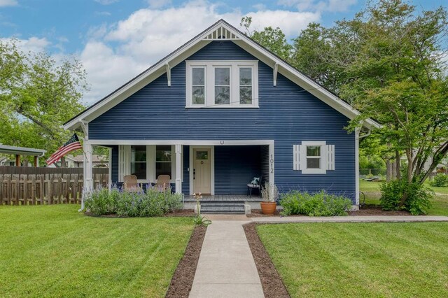 bungalow-style home with fence, a porch, and a front lawn