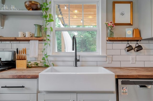 room details featuring backsplash, open shelves, dishwasher, a sink, and butcher block counters