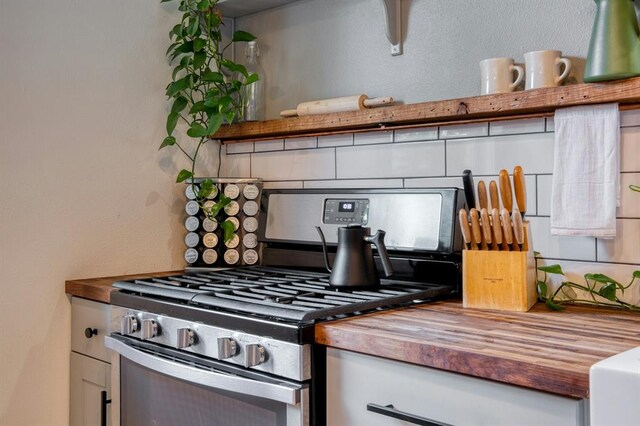 kitchen with gas stove, white cabinets, and wooden counters