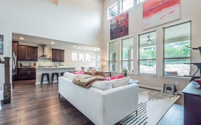 living area featuring a towering ceiling, recessed lighting, and dark wood-type flooring
