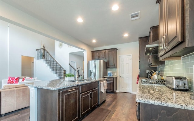 kitchen with dark wood-style flooring, dark brown cabinetry, range hood, a sink, and appliances with stainless steel finishes