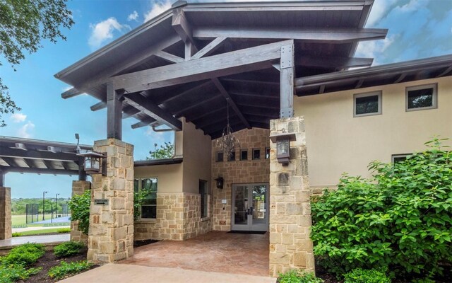 entrance to property featuring french doors, stone siding, and stucco siding
