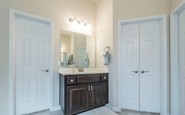 bathroom featuring vanity, baseboards, and a closet
