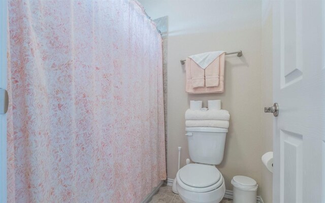full bathroom featuring a shower with shower curtain, tile patterned floors, and toilet